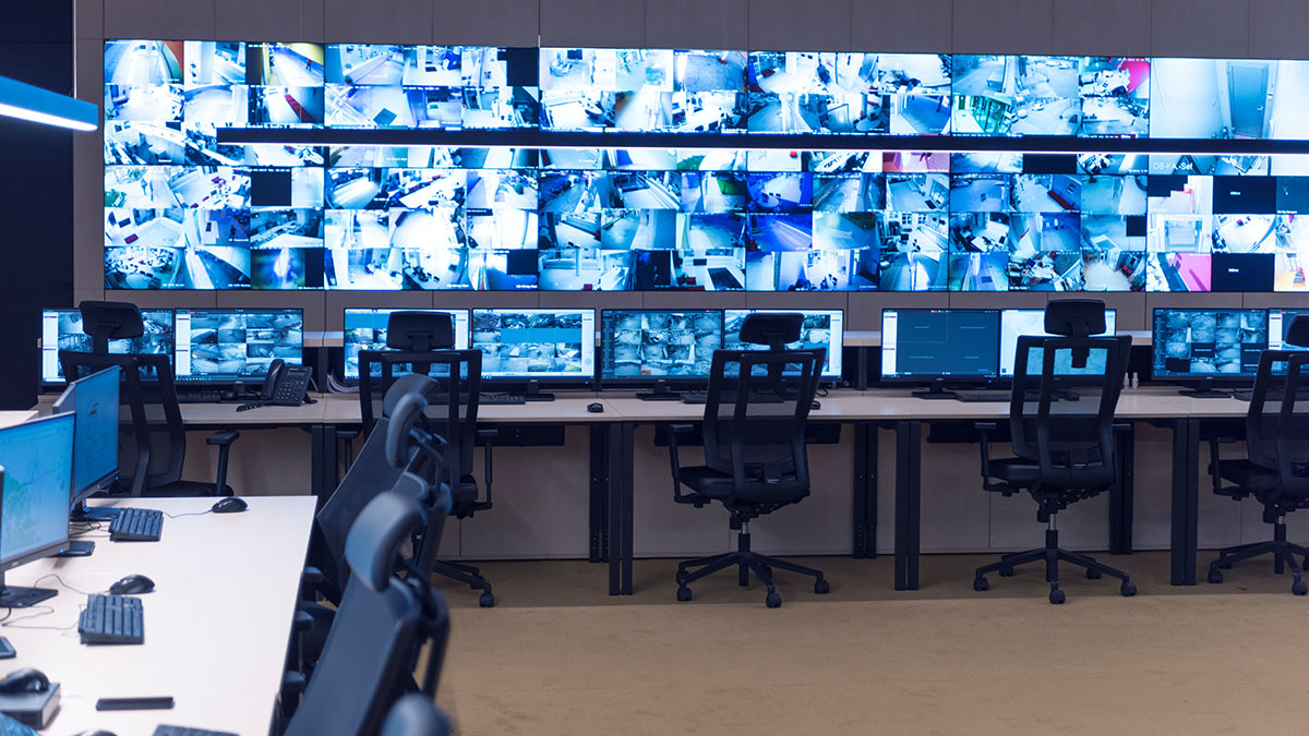 Security guard monitoring CCTV surveillance footage on multiple screens
